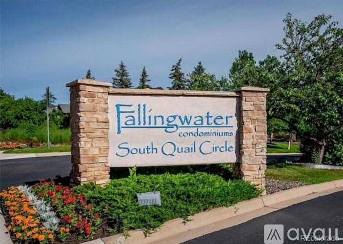 A sign for Fallingwater Condominiums South Quail Circle is displayed in front of a flower bed.