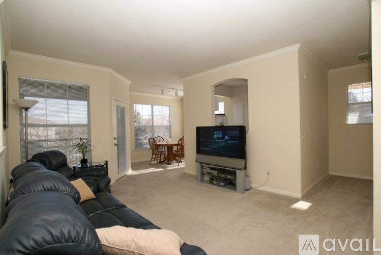 A living room with a black leather couch and a television.