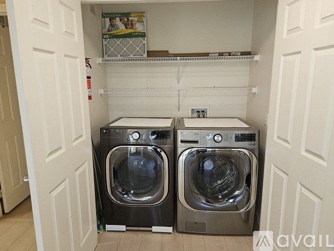 A dining room with a table set for two and a view of a fence and trees outside the window.