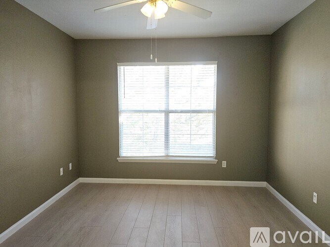 A room with a ceiling fan and a window with blinds.
