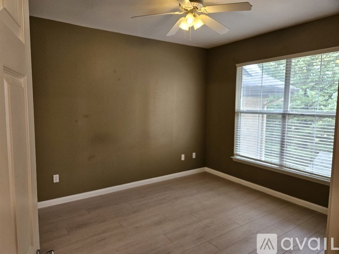 A room with a ceiling fan and a window with blinds.