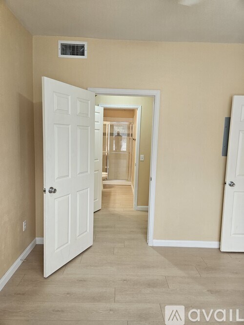 A hallway with a white door and a white wall.