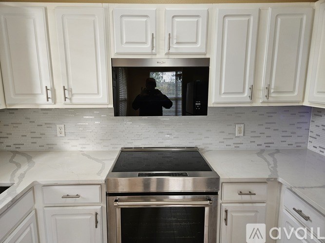A kitchen with white cabinets and a stainless steel oven.