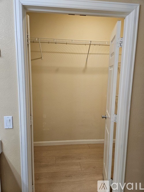 A white door is open to a room with a white wall and a white light switch.