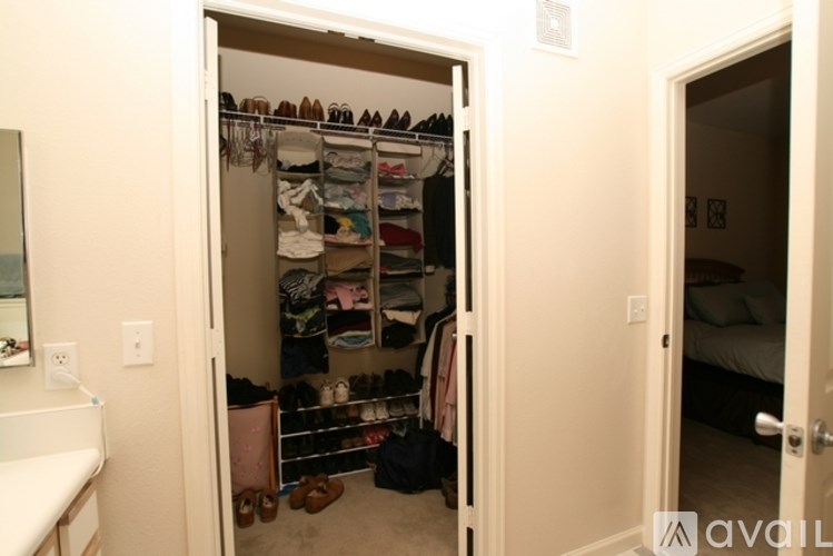 A room with a white door is open to a closet full of shoes.