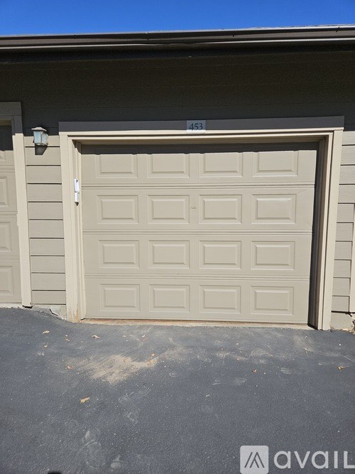 A beige garage door with the number 453 on the wall above it.
