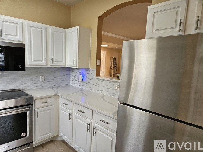 A kitchen with white cabinets and a stainless steel refrigerator.