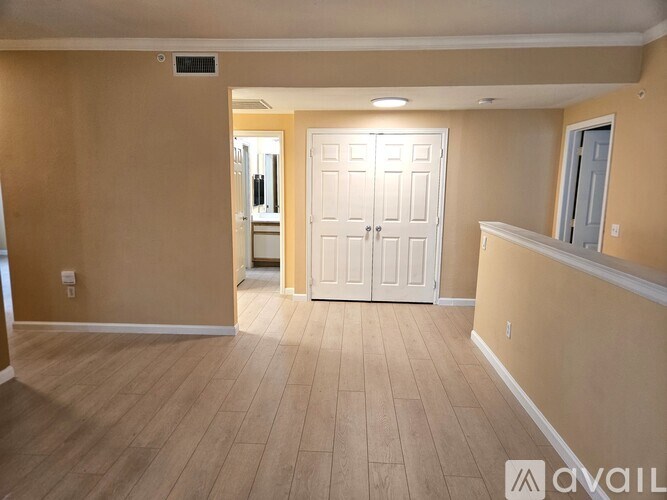 A room with a white door and wooden flooring.