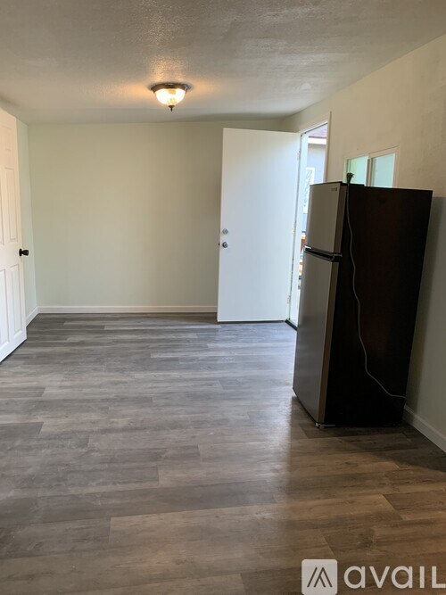 A kitchen area with a refrigerator and wooden flooring.