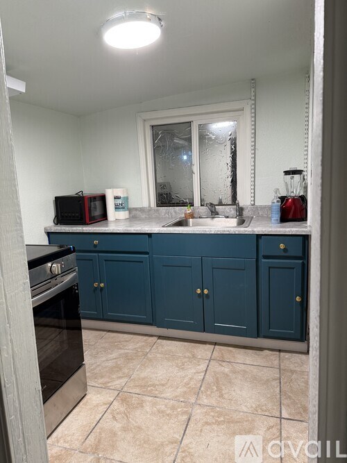 A kitchen with blue cabinets and a black oven.