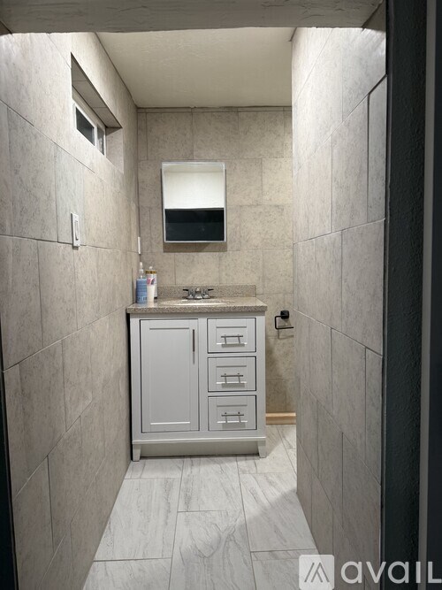 A bathroom with a grey cabinet and a mirror above it.