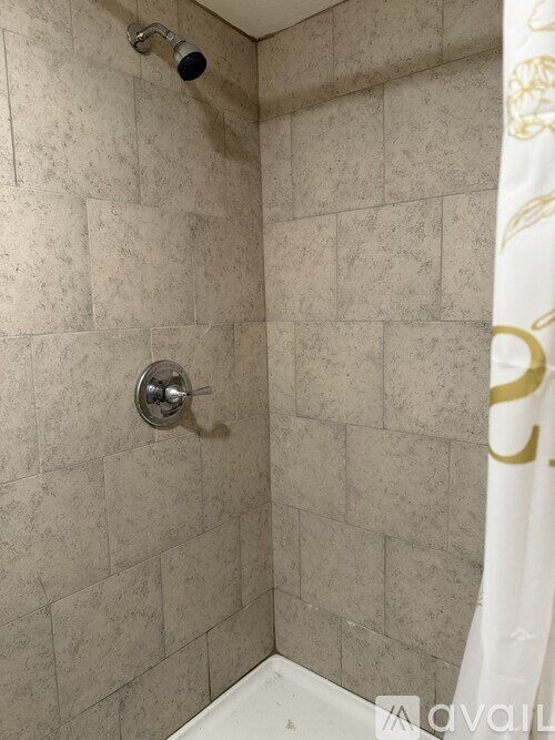 A shower with a gold patterned shower curtain.