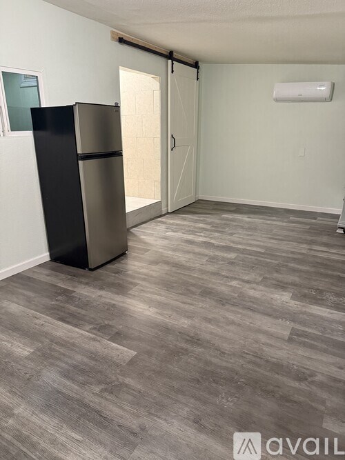 A room with a black fridge and a grey floor.