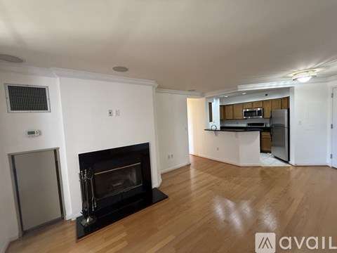 A living room with a fireplace and a kitchen in the background.