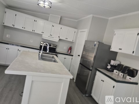 A kitchen with white cabinets and a marble island.