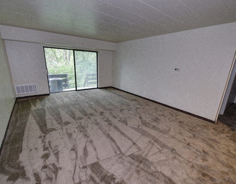 an empty living room with a large window and wood floors