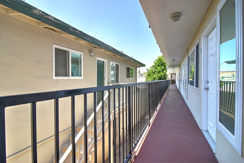 a balcony with a red walkway next to a building with white doors