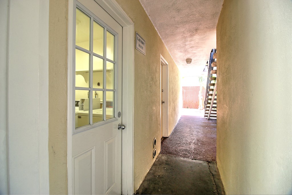 a hallway with a white door and a staircase in a building