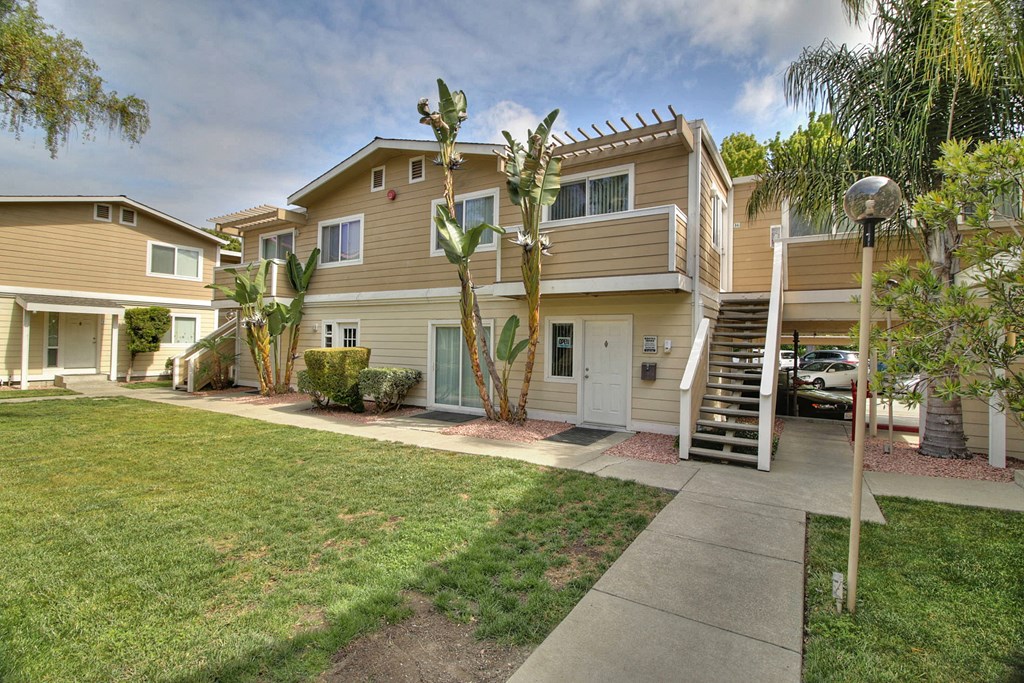 A house with a brown and beige exterior has a white door and a small porch.