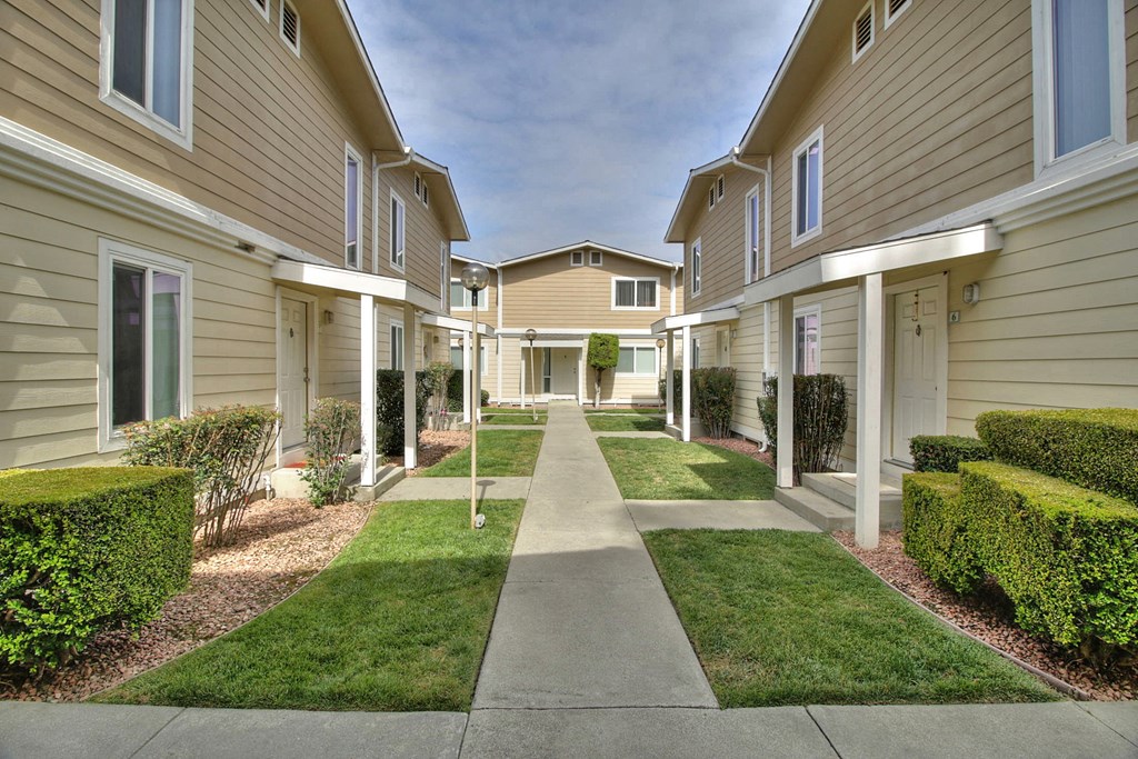 A long, narrow walkway separates apartment buildings.