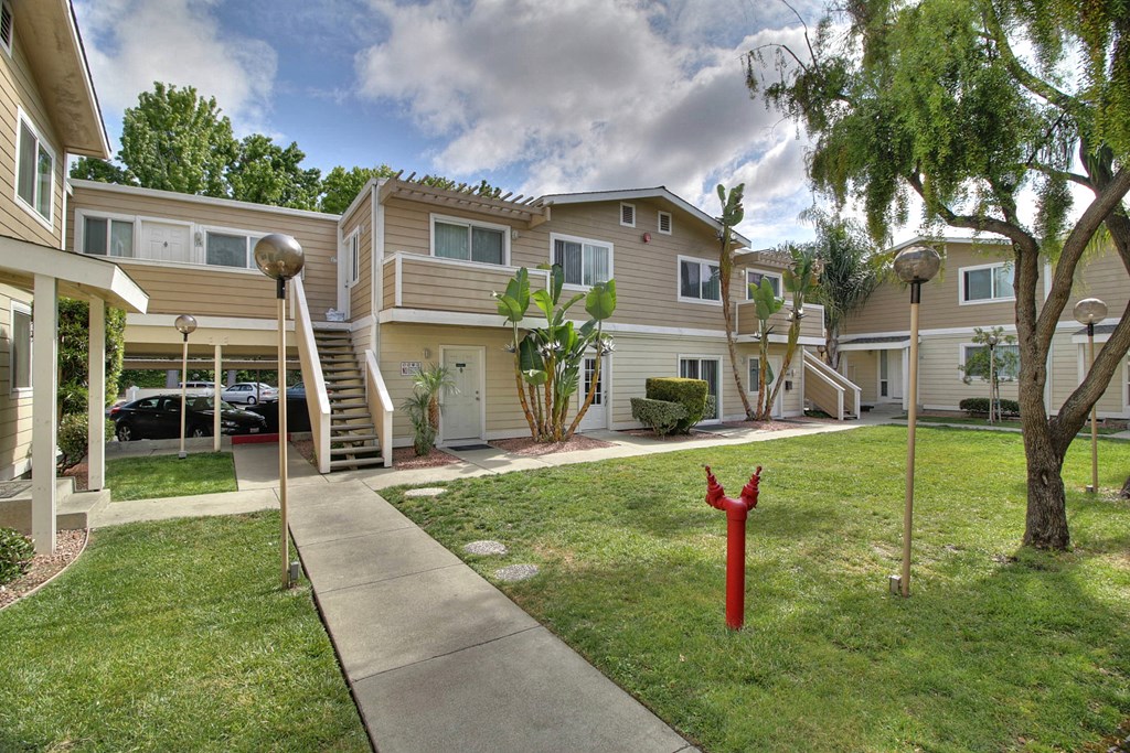 A red fire hydrant is in the grass next to a sidewalk.