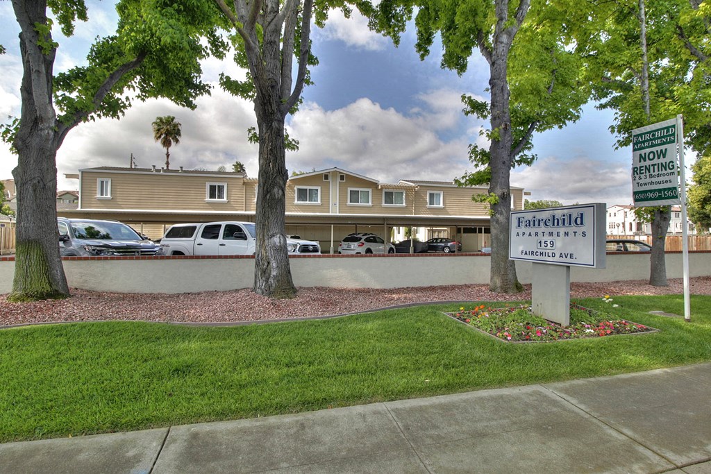 A sign for Fairchild Apartments stands in front of a building.