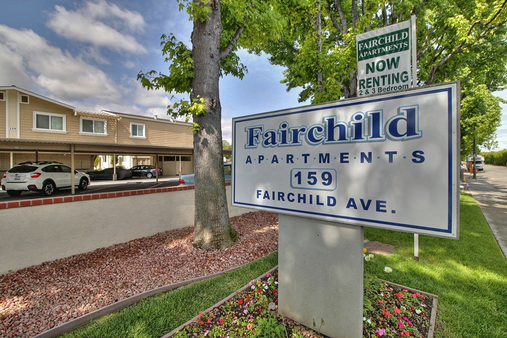 A sign for Fairchild Apartments stands in front of a building.