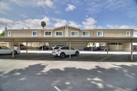 A white car is parked in a parking lot in front of a building.