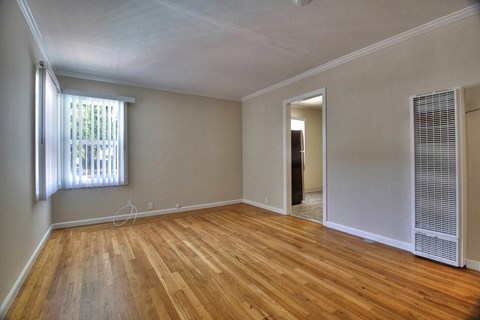 A room with wooden floors and a window with blinds.