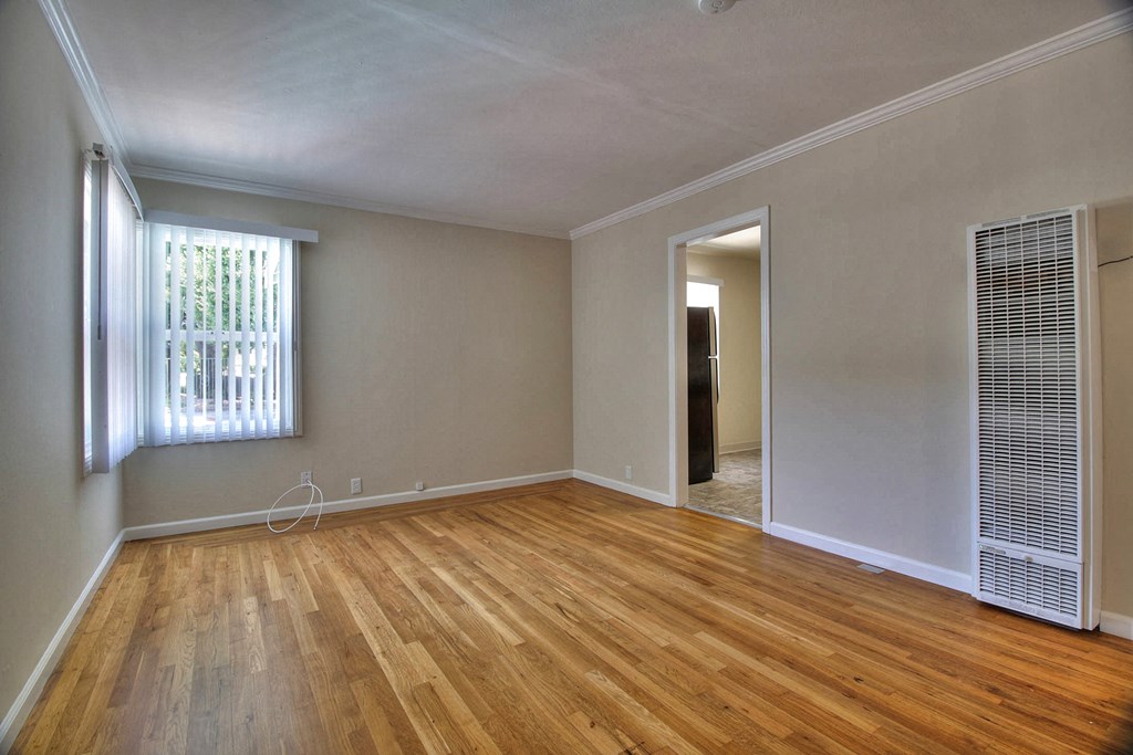 A room with wooden floors and a window with blinds.