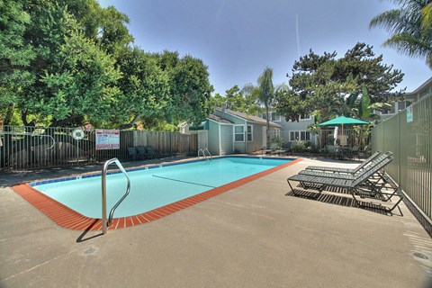 A pool surrounded by trees and a fence with a sign on it.