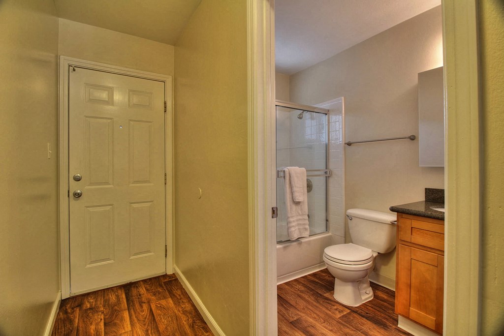 A white door is in a room with a toilet and a shower.