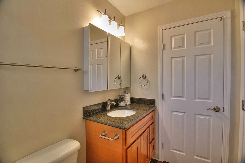 A bathroom with a toilet, sink, and mirror.