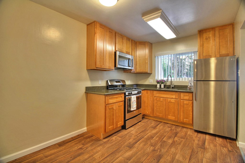A kitchen with wooden cabinets and a stainless steel refrigerator.