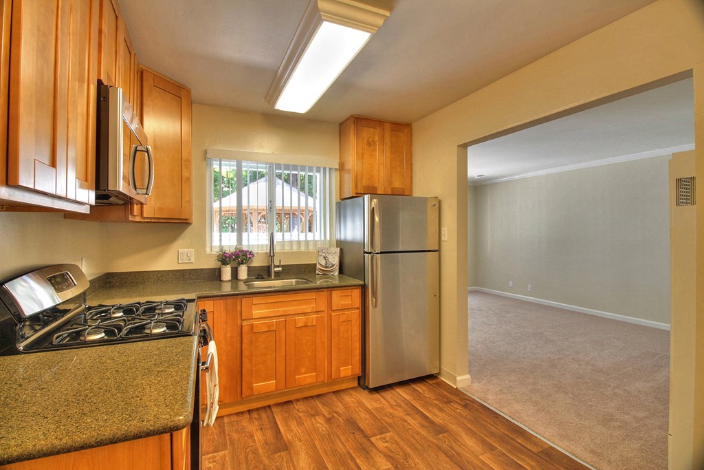 A kitchen with wooden cabinets and a stainless steel refrigerator.