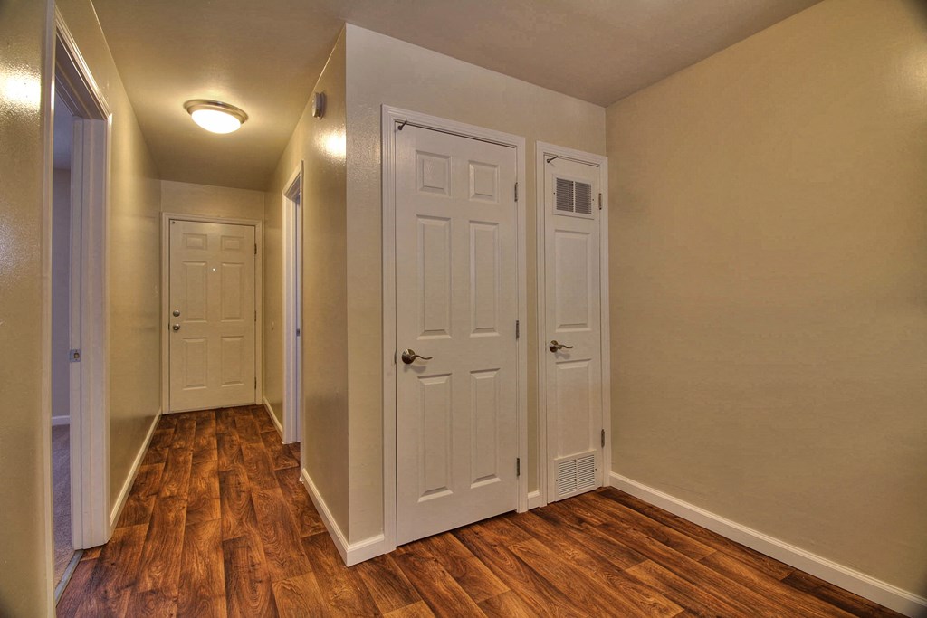A hallway with three doors and wood floors.