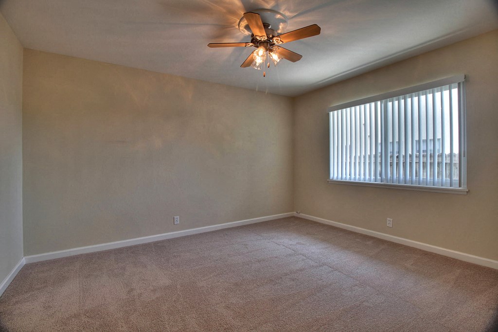 A room with a ceiling fan and a window with blinds.