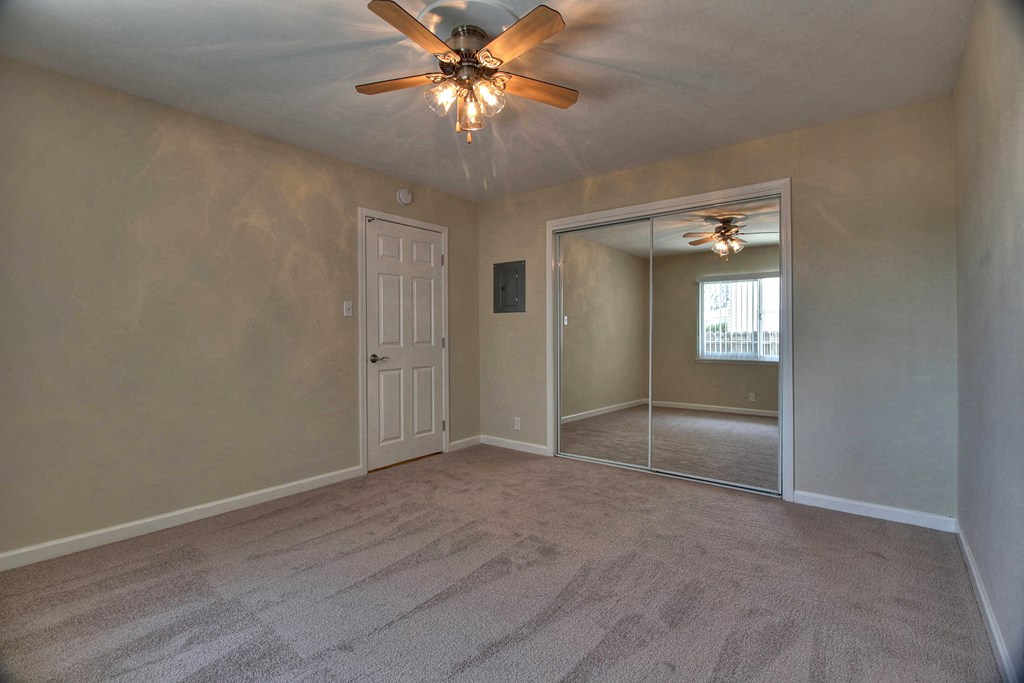 A room with a ceiling fan and carpeted floor.