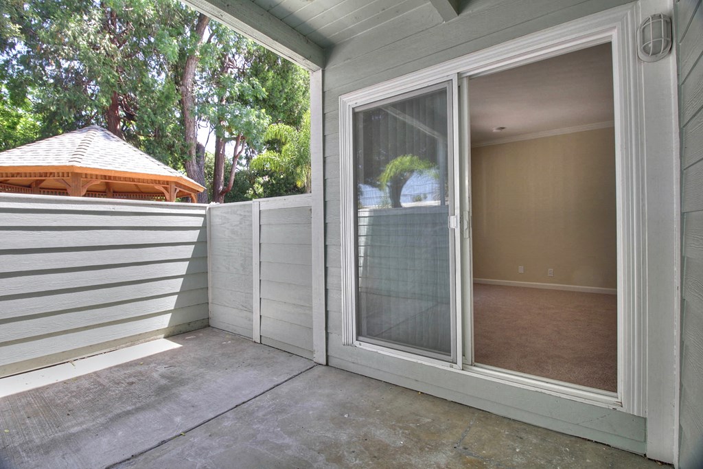A patio with a sliding glass door leading to a room.