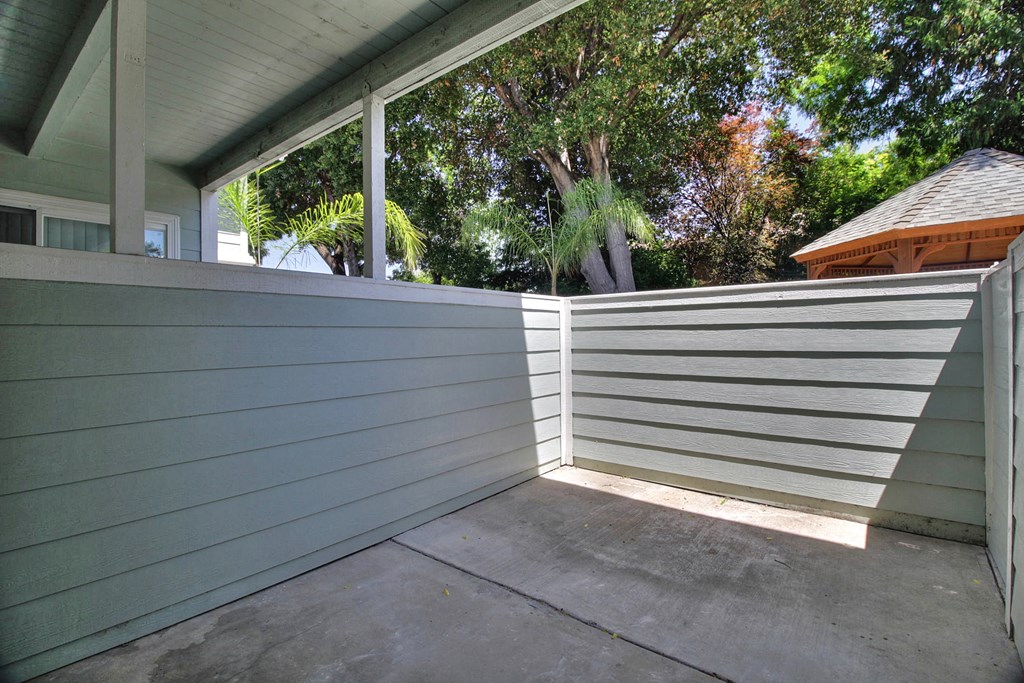 A patio with a grey wall and a white slatted fence.
