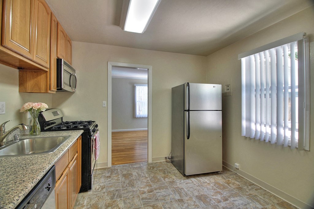 A kitchen with a granite counter top and a refrigerator.