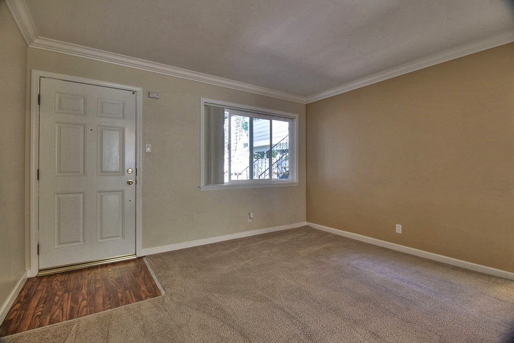 A room with a white door and a window with a view of a building outside.