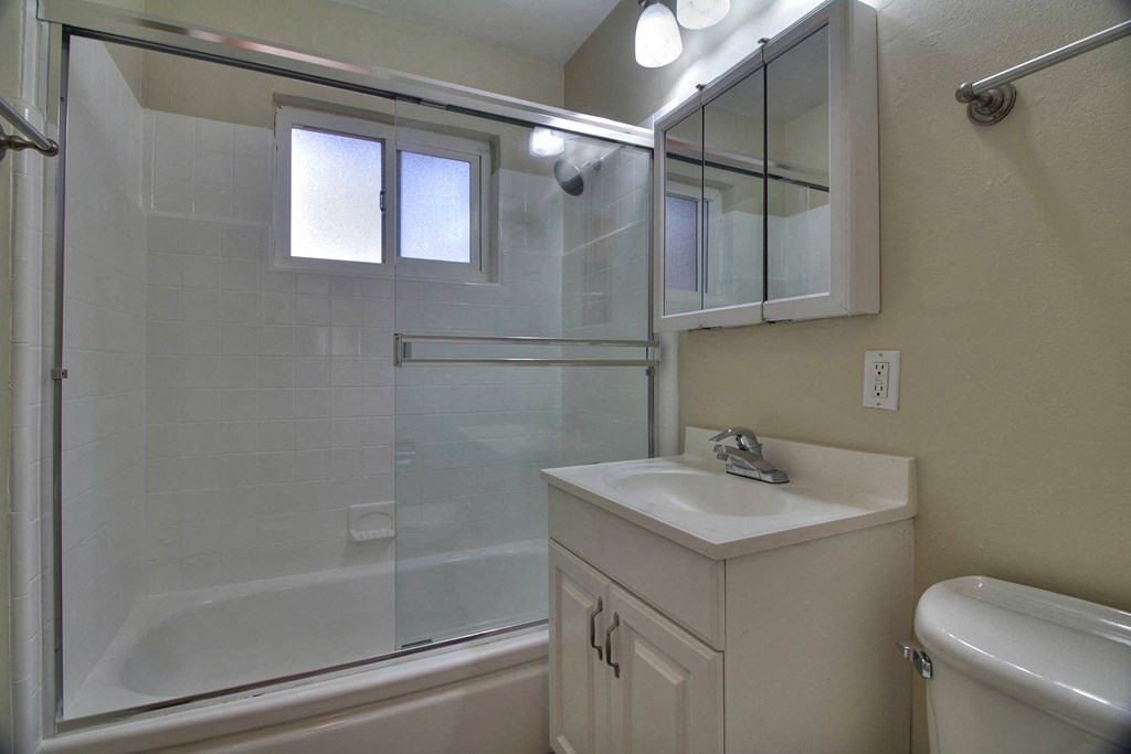 A white sink is on a white cabinet in a white bathroom.