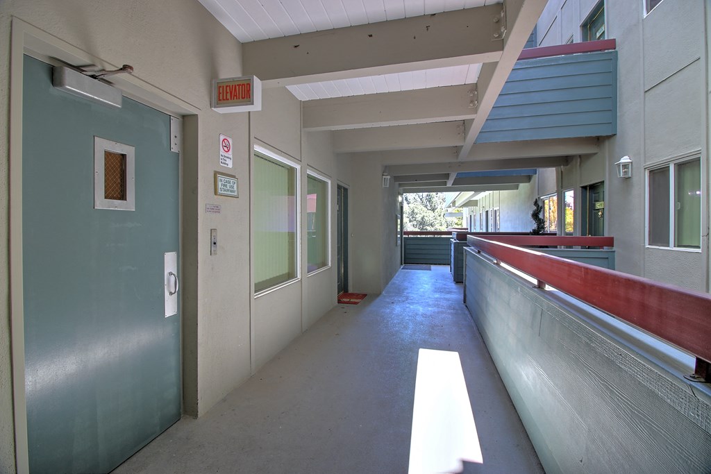 a corridor of a building with doors and a bench