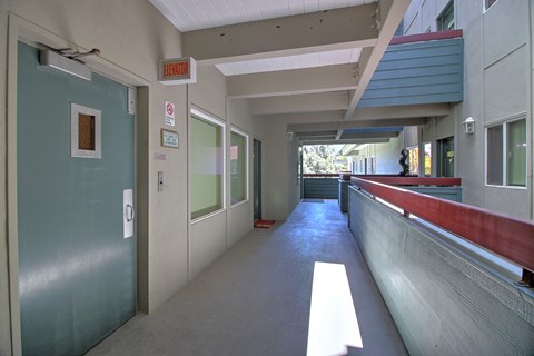 A long hallway with a red line on the wall and an elevator in the distance.
