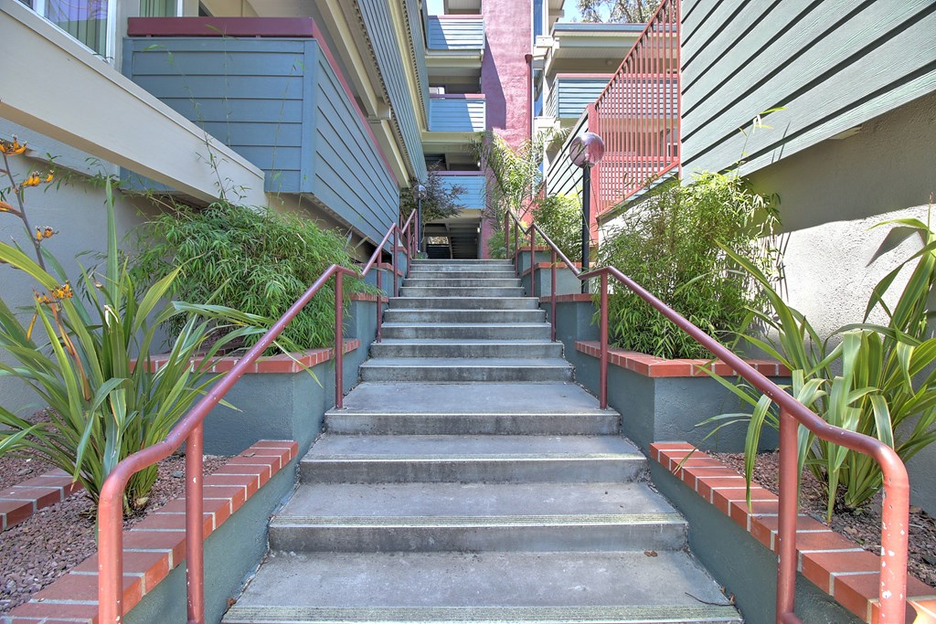 a flight of concrete stairs with red railings going down a