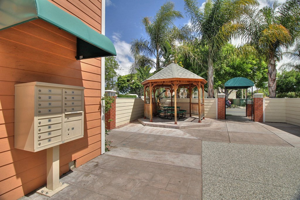 a gazebo on the side of a house with a patio