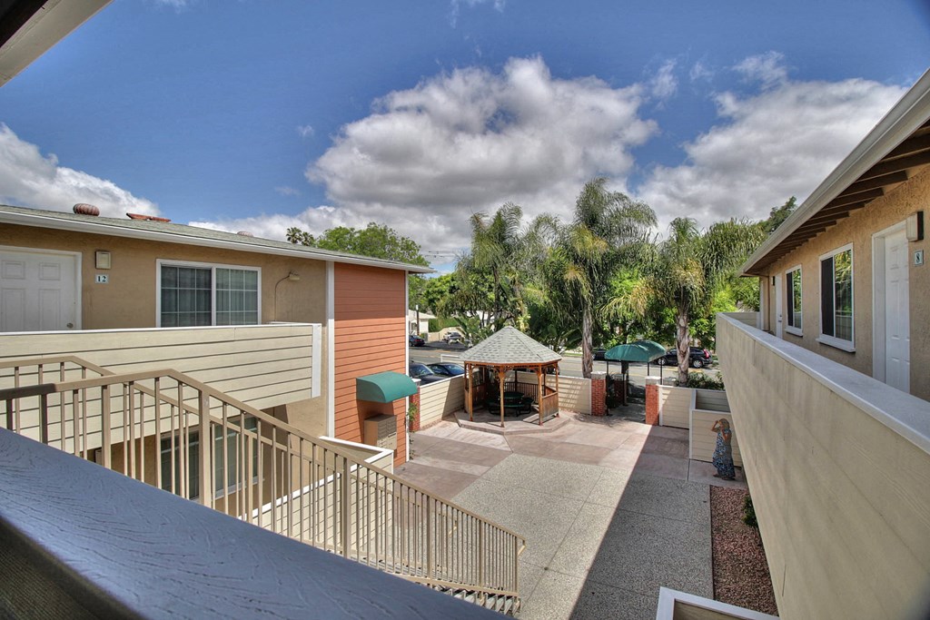 a patio with a table and a gazebo in front of some apartments