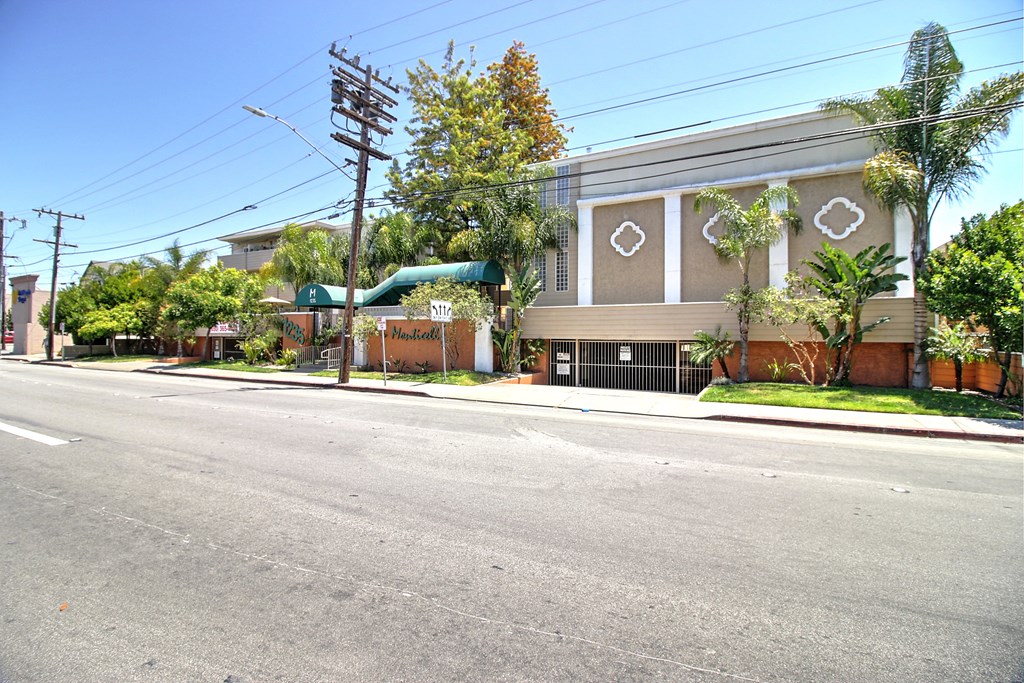 A brown building with a green awning is on the corner of a street.