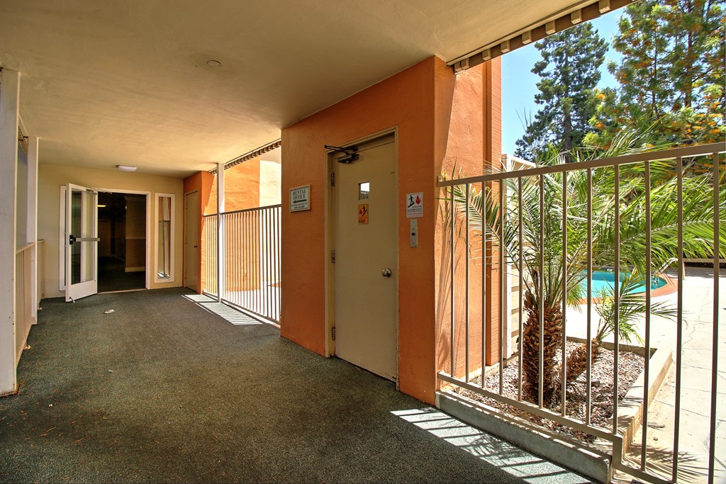 A long hallway with doors on both sides and a pool in the distance.